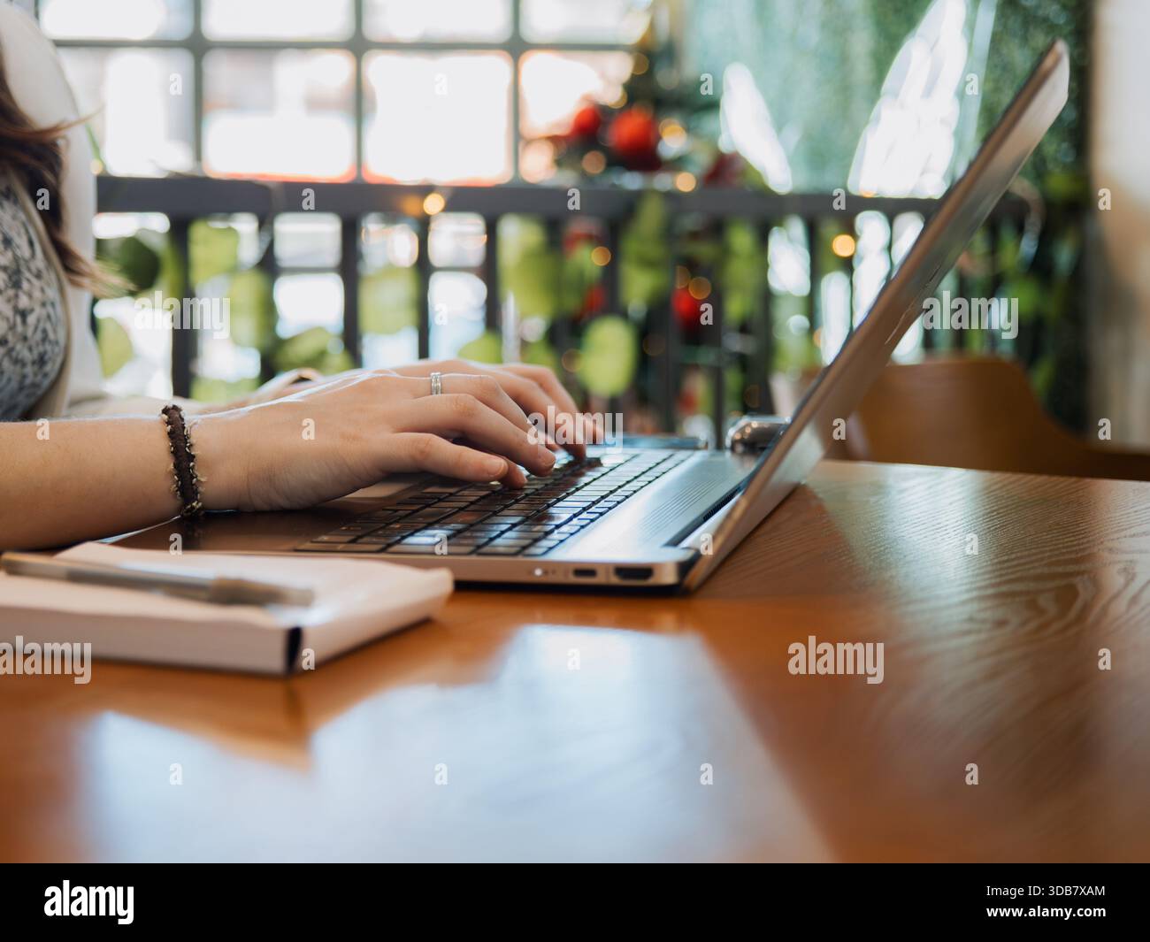 Nahaufnahme der Hände mit einem Laptop auf einem Schreibtisch mit Notebook in der Nähe. Arbeits-, Studien- und Online-Produktivitätskonzept. Stockfoto
