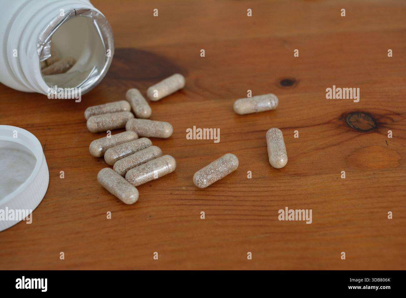 Ergänzungskapseln, die auf einer Holzplatte verschüttet werden 2 Stockfoto
