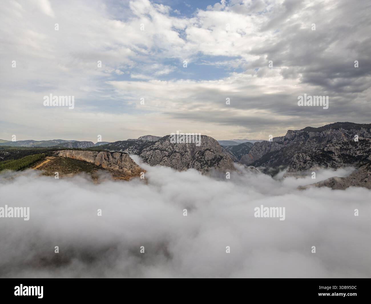 Berggipfel, die sich über Wolken unter dramatischem Himmel erheben Stockfoto