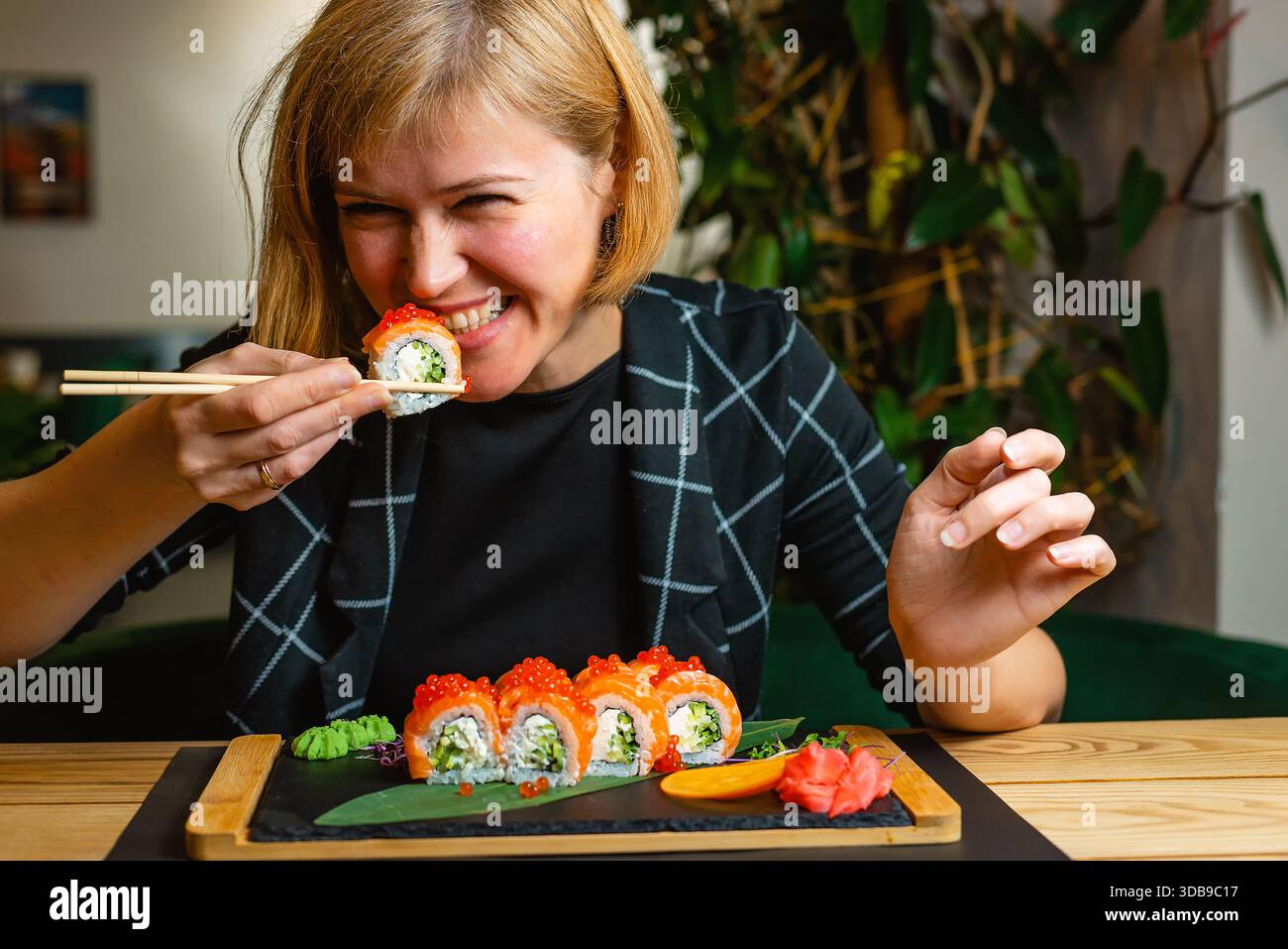 Die Frau beißt während eines entspannten Essens gerne in eine Sushi-Rolle. Stockfoto