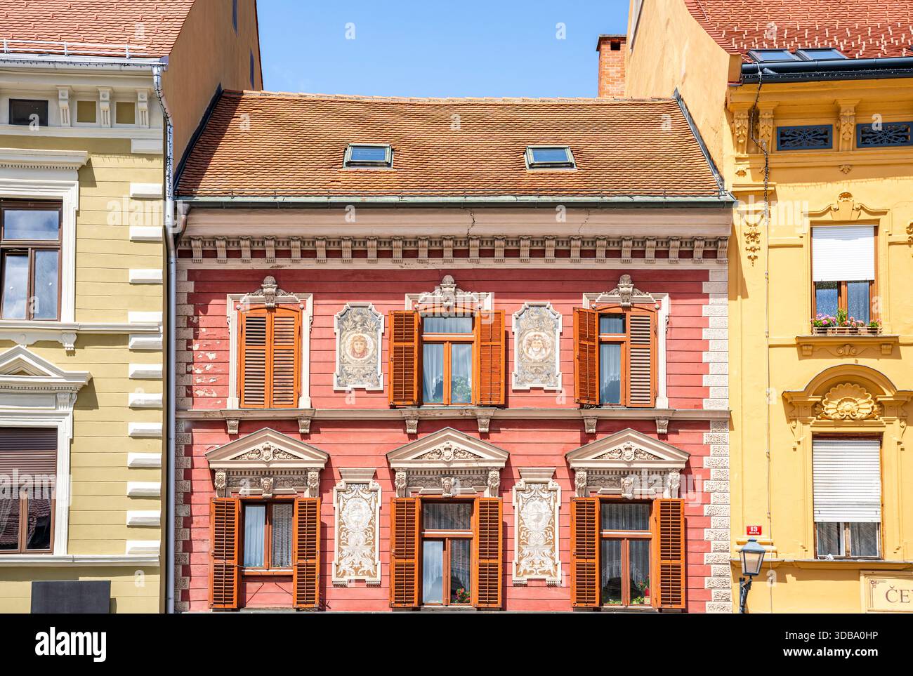 Rot verzierte Fassade mit Fenstern, Tympanen und Kunstwerken auf dem Hauptplatz (Glavni Trg) von Maribor, Slowenien Stockfoto