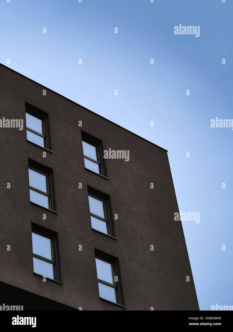 Moderne Wohnhausfassade mit hohen Fenstern und klarem Himmel, geeignet als minimalistische Immobilien oder urbanes Design Hintergrund. Stockfoto