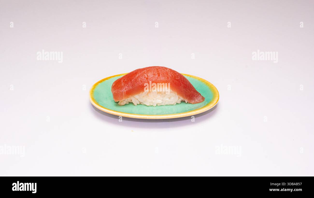 Klassisches Thunfisch-Nigiri-Sushi serviert auf grüner Keramikplatte isoliert auf weißem Hintergrund. Stockfoto