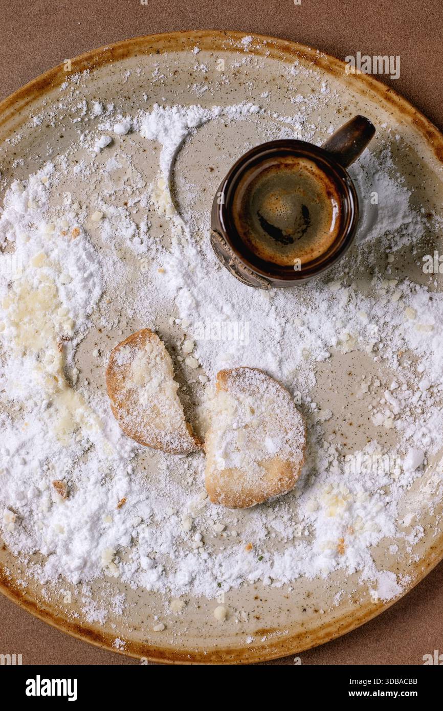 Letztes defektes Cookie. Hausgemachter Shortbread-Keks mit Puderzucker und einer Tasse frisch gebrühten Espresso. Hintergrund in der Farbe der Yea von 2025 Stockfoto