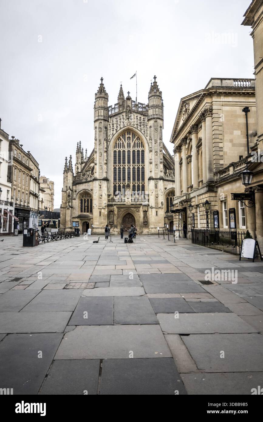 Der Blick auf die große Kathedrale erhebt sich majestätisch über dem weitläufigen Steinplatz und wirft lange Schatten im gedämpften Licht, Wells, England, Vereinigtes Königreich Stockfoto