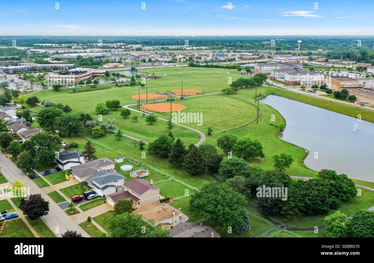 Drohnenfotografie des Centennial Park in Addison Illinois zeigt an einem Sommertag Baseballfelder, Teichgrünflächen und ein vorstädtisches Viertel. Stockfoto
