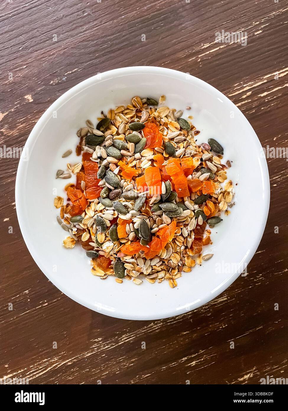 Joghurt in einer Schüssel mit geröstetem Hafer, gemischten Samen und getrockneten Früchten zum Frühstück. Einfache, ausgewogene Mahlzeit zu Hause zubereitet und verzehrfertig Stockfoto