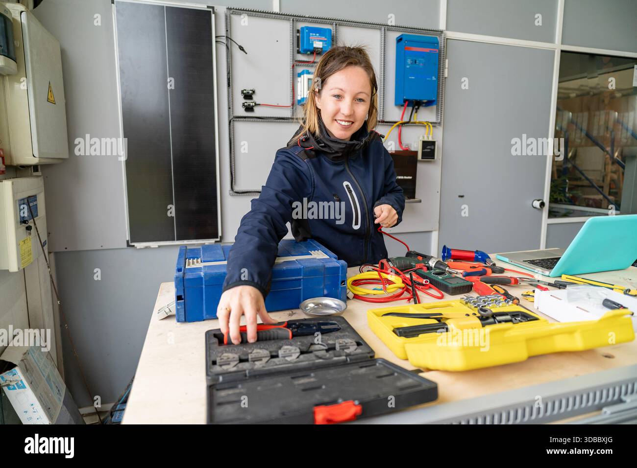 Frau lächelt, bereitet Werkzeuge für die Verkabelung und Wartung von Solaranlagen vor Stockfoto