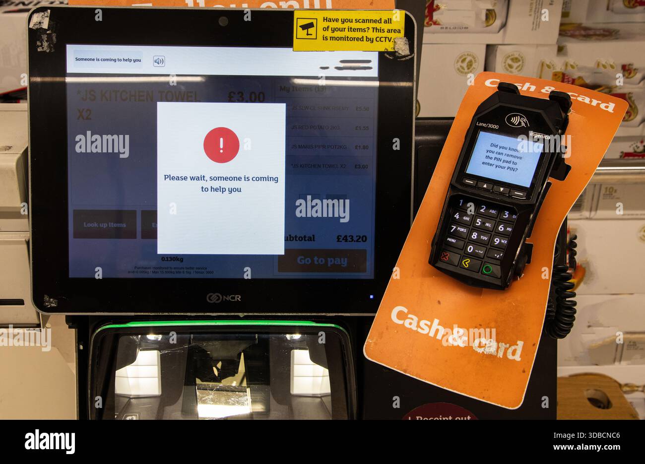 Self-Service-Checkout-Bildschirm in einem Supermarkt mit der Meldung „Bitte warten, jemand kommt, um Ihnen zu helfen“, wobei die technischen Probleme im Einzelhandel hervorgehoben werden. Stockfoto