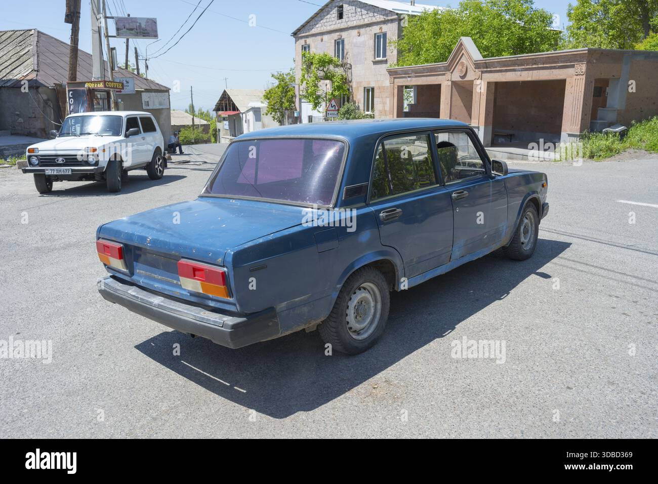 Ein blaues Auto an einer städtischen Kreuzung an einem klaren sonnigen Tag, Lada 2107, auch WAS-2107, VAZ-2107, Lada Nova oder Lada Riva fährt ohne Kennzeichen, A Stockfoto