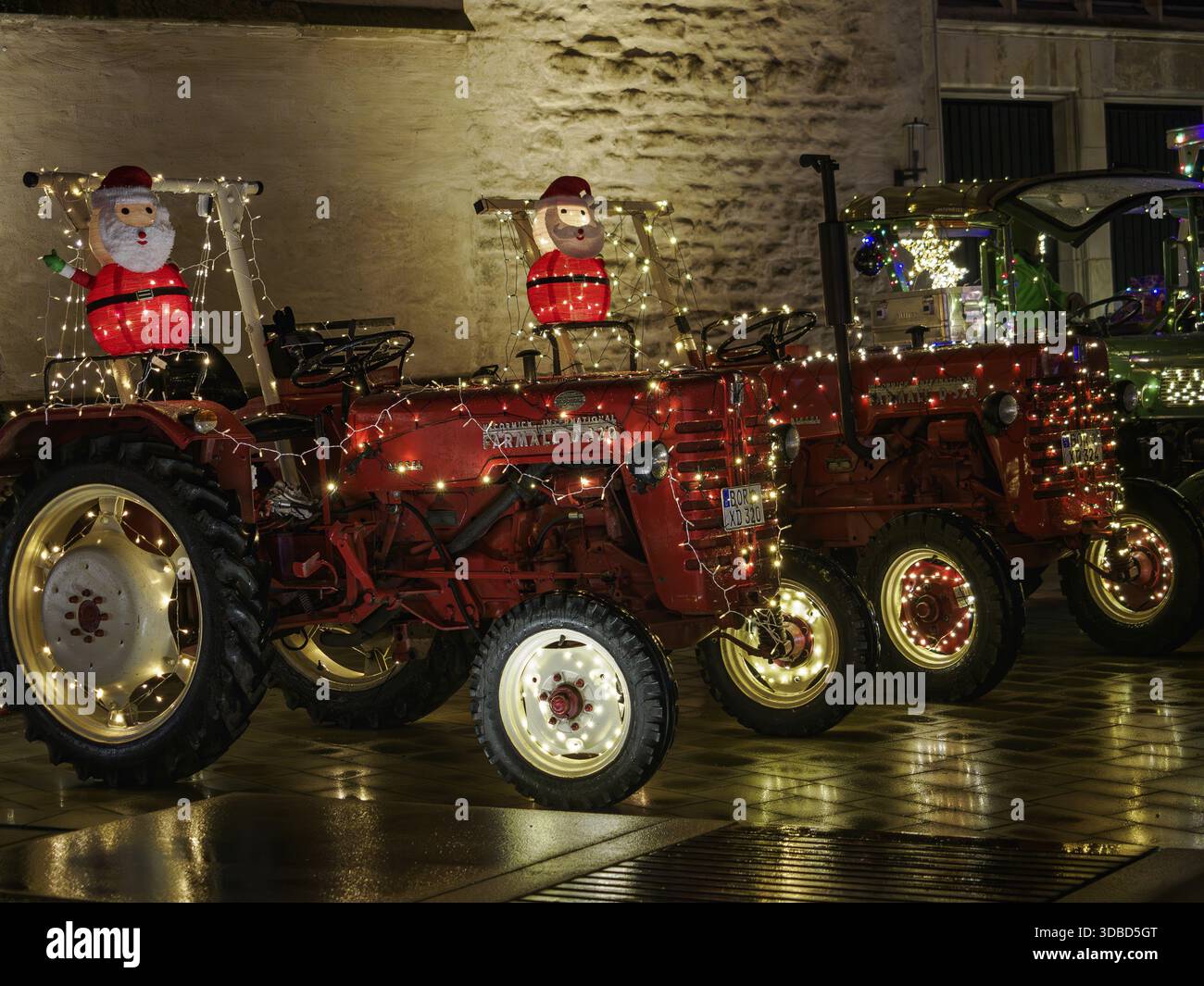 Rote Traktoren mit Weihnachtsbeleuchtung und Weihnachtsmannfiguren in festlicher Umgebung, Borken, Münsterland, Deutschland Stockfoto