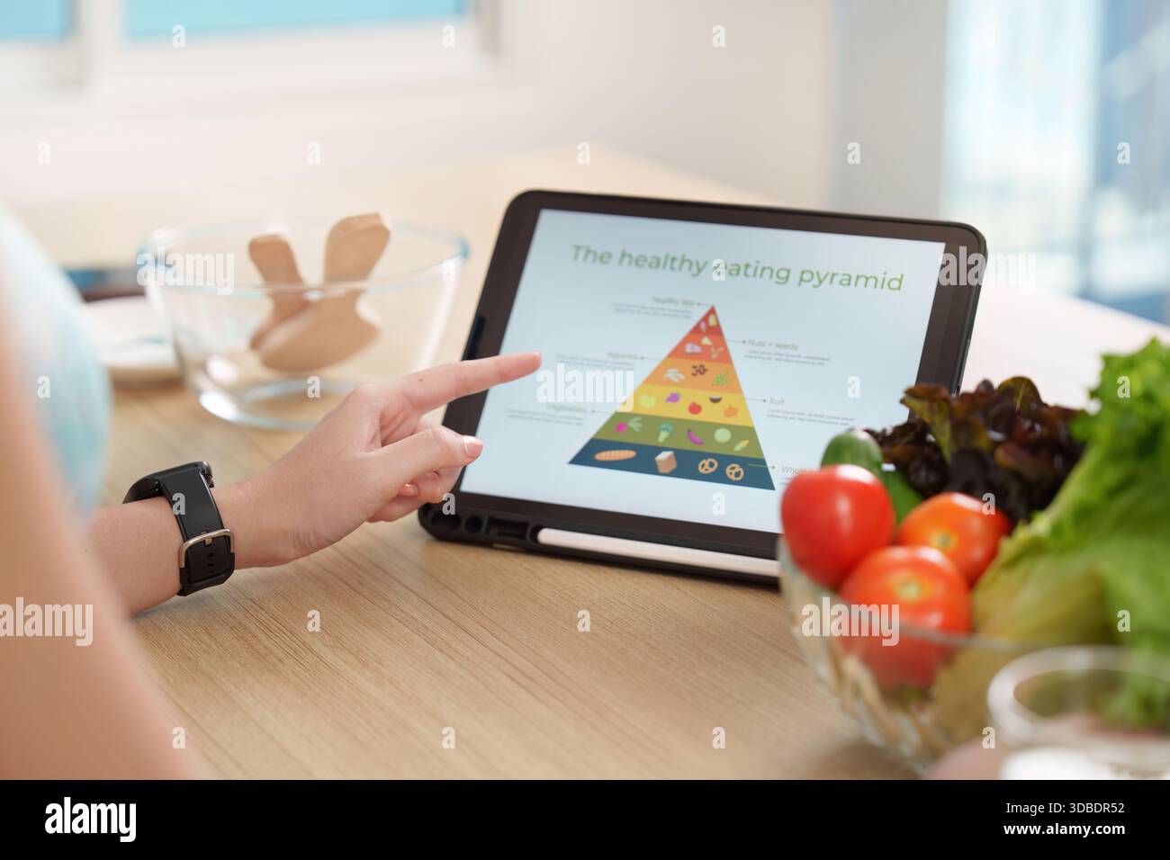 Gesunde Ernährung Pyramide auf Tablette. Eine Person, die Ernährungsrichtlinien für eine ausgewogene Ernährung erforscht. Stockfoto