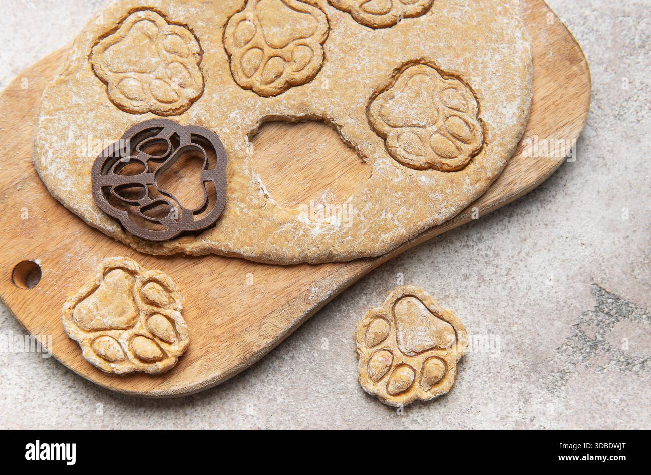 Teig, Cutter und Pfoten drucken Kekse auf ein Holzbrett und bereiten hausgemachte Haustierspezialitäten zu Stockfoto