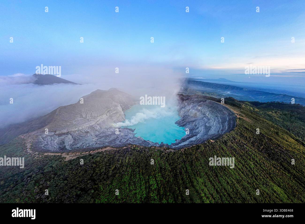 Spektakulärer Vulkan Ijen auf der Insel Java in Indonesien, Blick aus der Vogelperspektive auf einen Vulkankrater und einen blauen vulkanischen See mit dampfenden Lüftungsöffnungen bei Sonnenaufgang Stockfoto