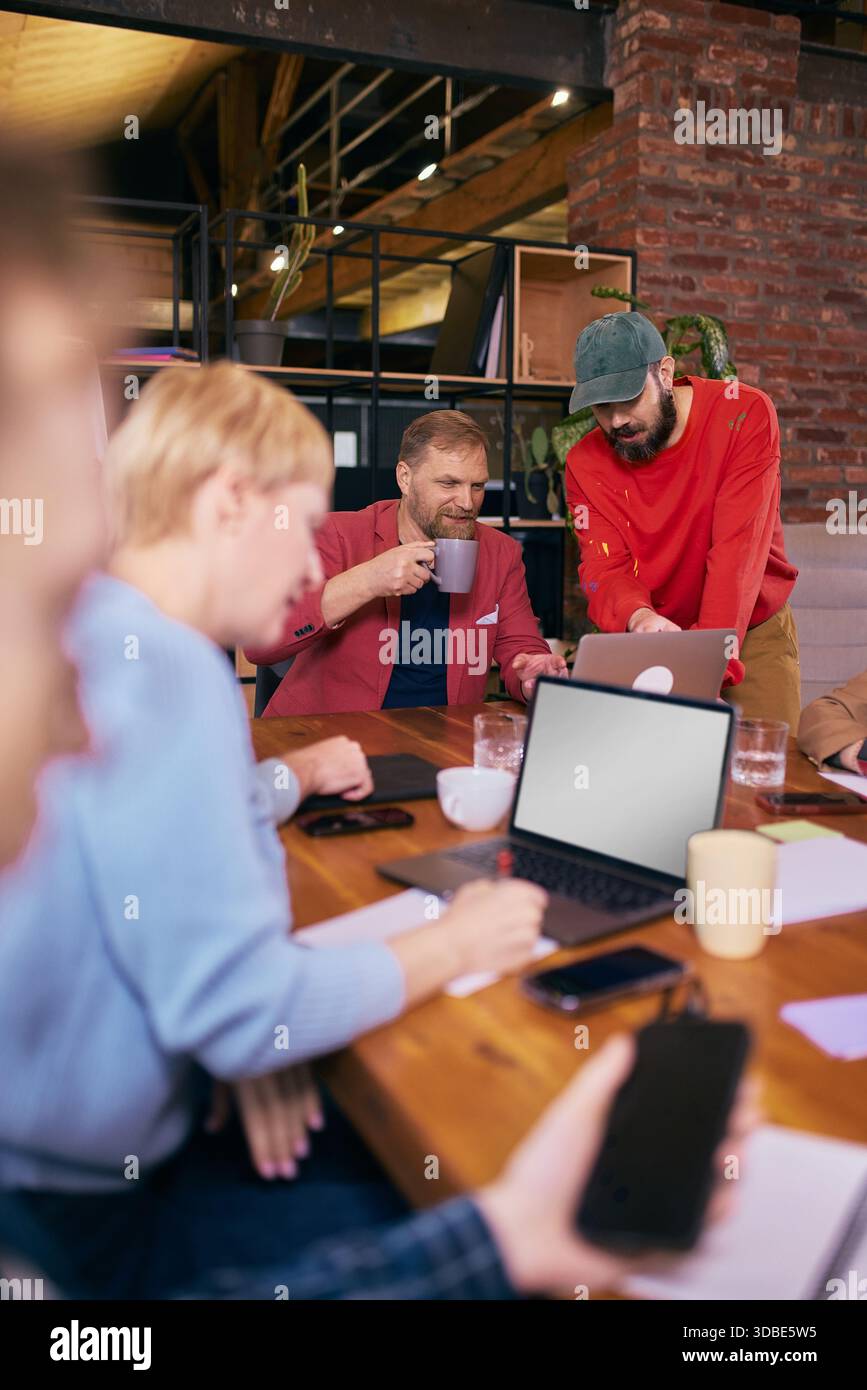 Team prüft Inhalte gemeinsam in entspannter Coworking-Umgebung. Stockfoto