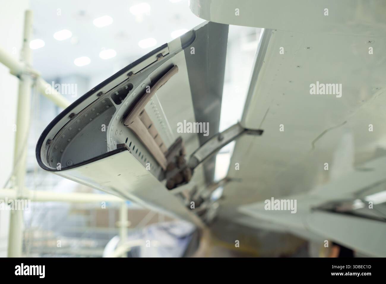 Nahaufnahme eines Flugzeugflügelklappenmechanismus in einer Instandhaltungseinrichtung. Werkzeuge und Ausrüstung sind sichtbar, was die komplizierte Konstruktion unterstreicht Stockfoto