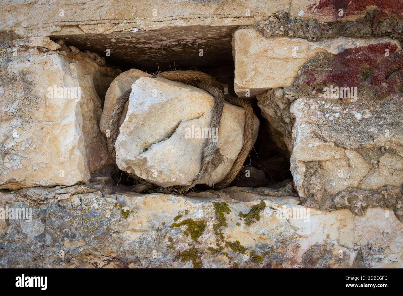 Loch in einer Steinmauer mit einer Lücke für einen Stein, der geschnürt ist. Verlassenes Haus auf dem Land. Paxos, Griechenland. Stockfoto
