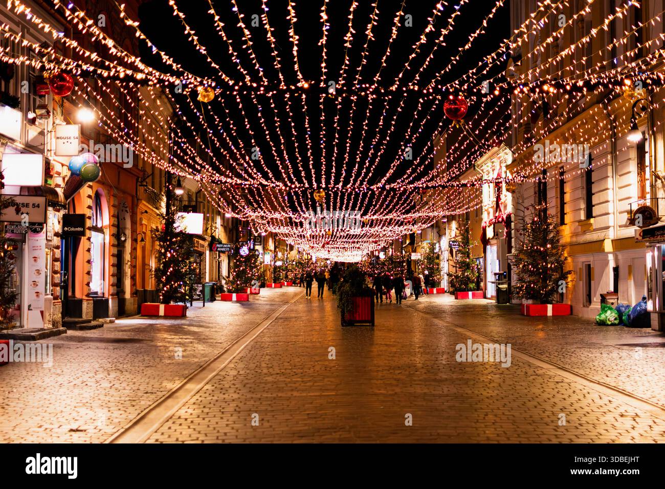 Die Fußgängerzone Republicii in Brasov, Rumänien, ist während der Weihnachtszeit mit warmen Weihnachtslichtern und Ornamenten dekoriert. Leute, die in der d Stockfoto