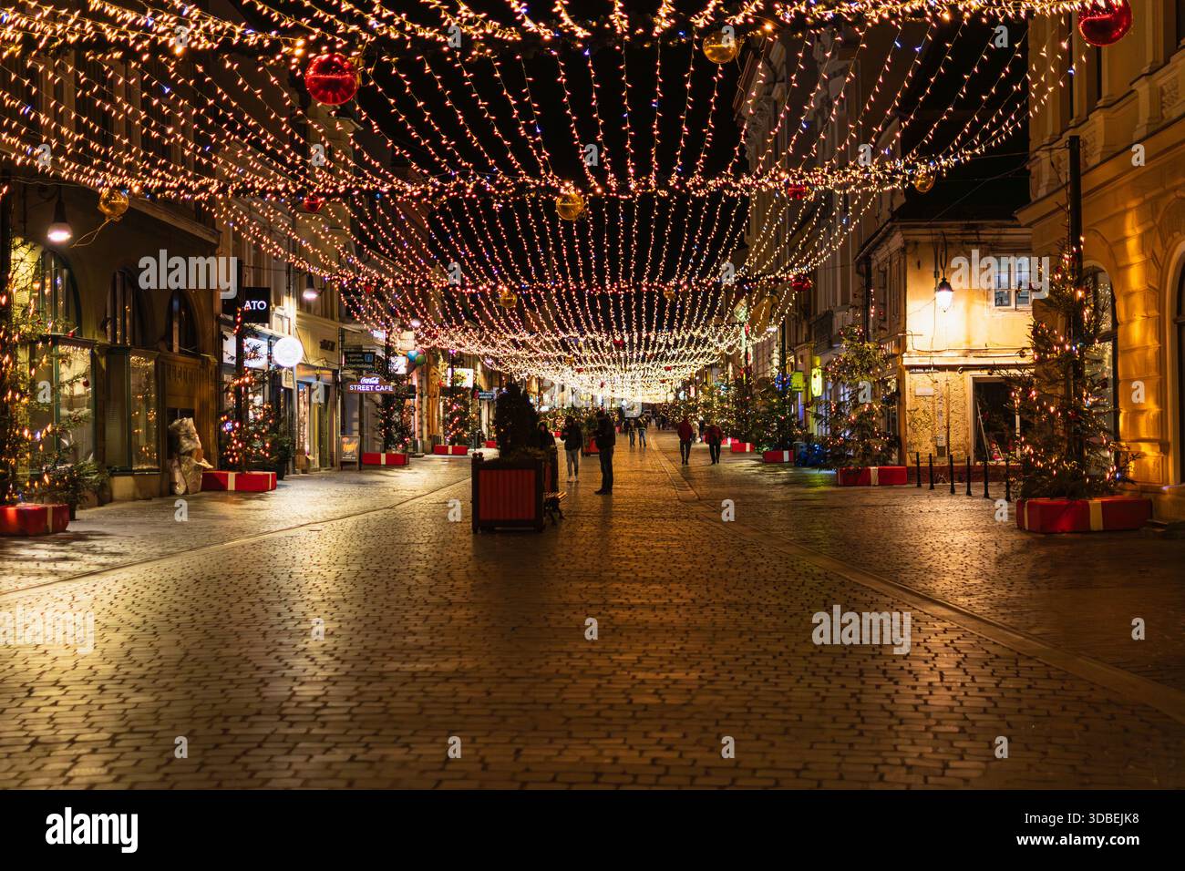 Die Fußgängerzone Republicii in Brasov, Rumänien, ist während der Weihnachtszeit mit warmen Weihnachtslichtern und Ornamenten dekoriert. Leute, die in der d Stockfoto