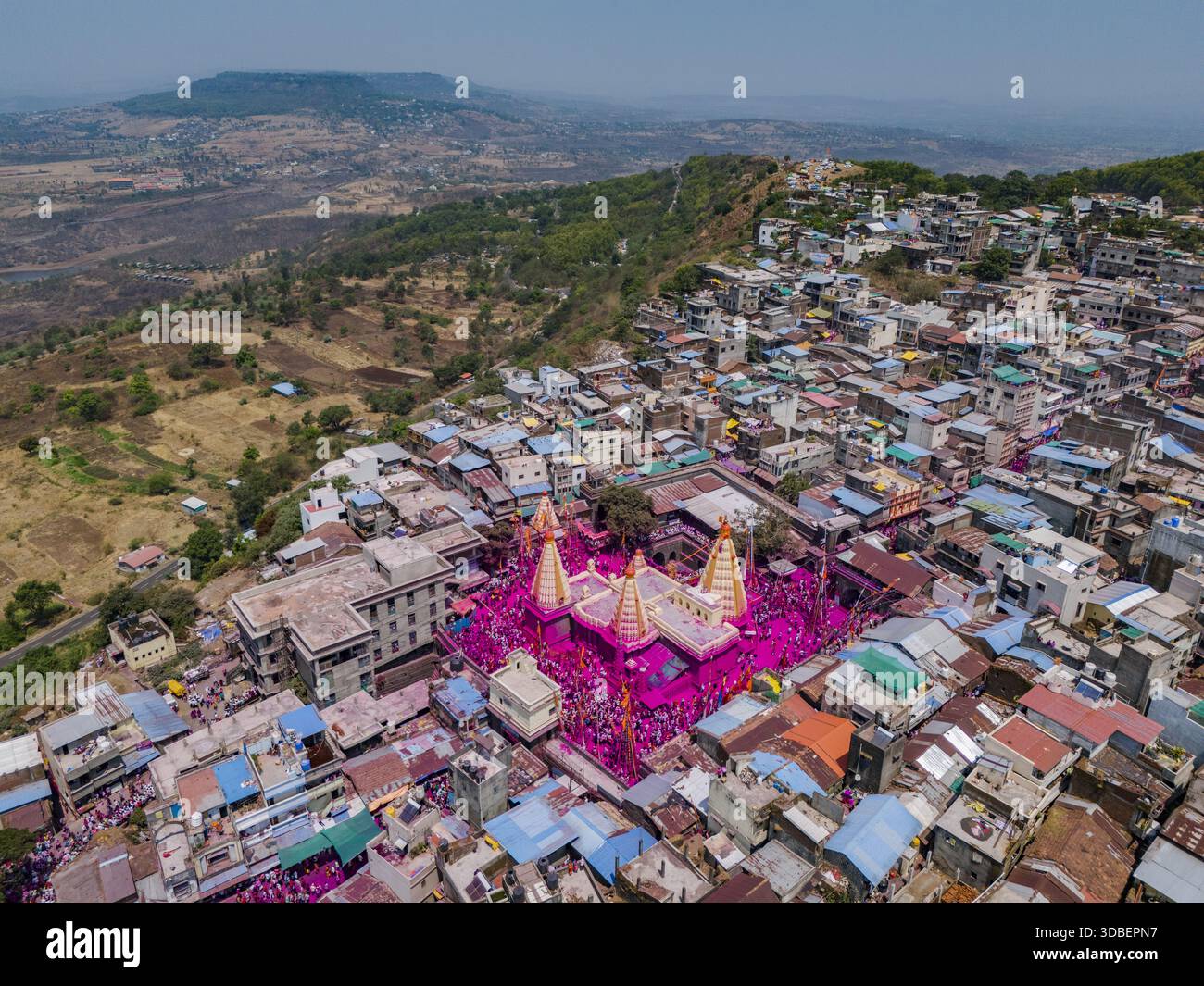 Aus der Vogelperspektive des lebendigen Jyotiba Tempels, umgeben von einem Meer aus rosa und orangen Tönen inmitten der dicht gepackten Gebäude, im Kontrast zu den fernen Gebäuden Stockfoto