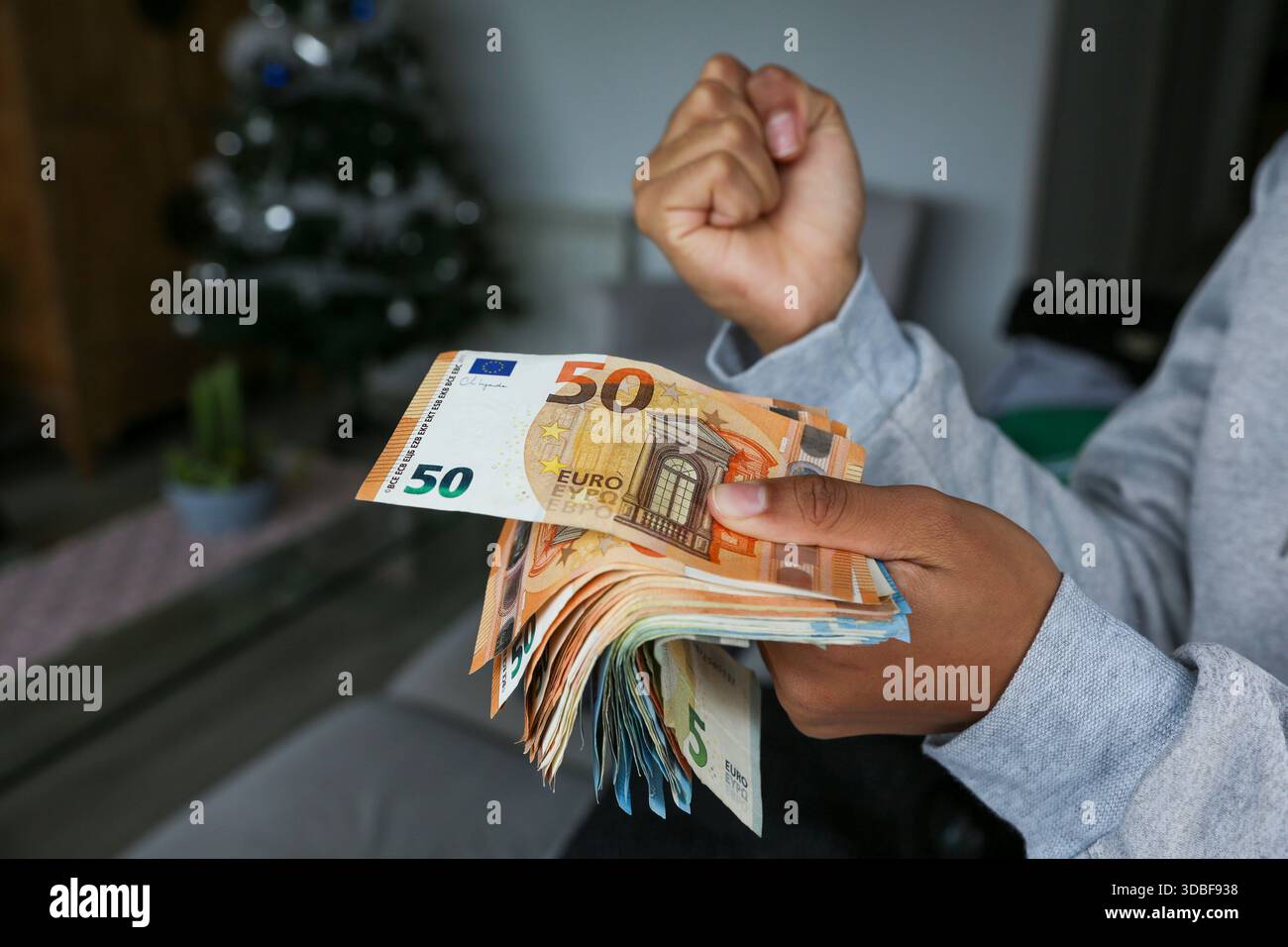 Ein Bündel Euro-Banknoten, gehalten von den Händen einer hellhäutigen Afroamerikanerin, die feiert, dass sie dieses Geld hat Stockfoto