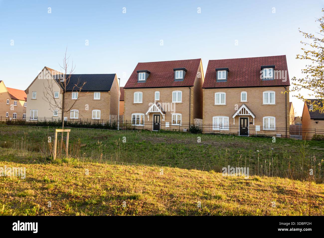 Neu gebaute Häuser in einem neuen Wohnhaus am Stadtrand in England bei Sonnenuntergang im Frühjahr Stockfoto