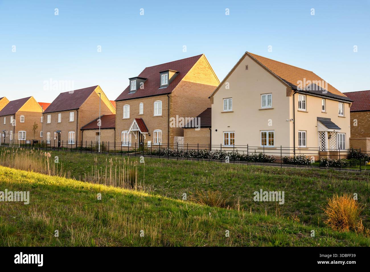 Neue Häuser in einer Vorstadtsiedlung unter klarem Himmel bei Sonnenuntergang Stockfoto