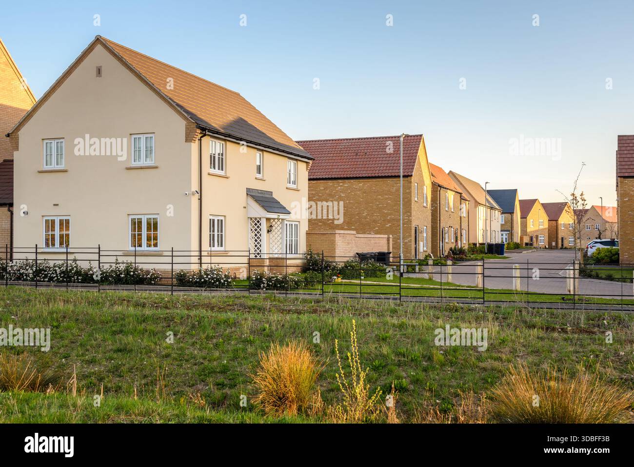 Neu gebaute Einzel- und Doppelhäuser entlang einer Straße in einem Wohngebiet am Stadtrand bei Sonnenuntergang im Frühjahr Stockfoto