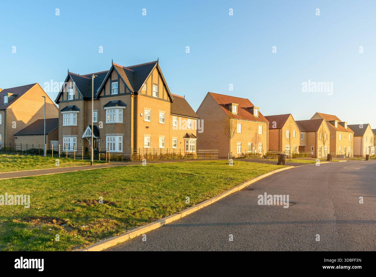 Reihe neu gebauter Einfamilienhäuser entlang einer Straße in einem neuen Wohngebiet bei Sonnenuntergang Stockfoto