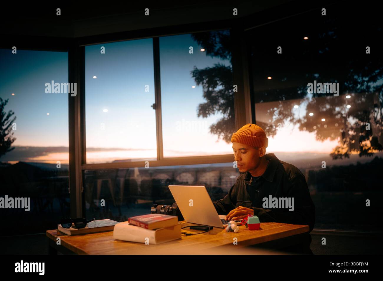 Ein fokussierter junger Mensch, der spät am Sonnenuntergang arbeitet Stockfoto