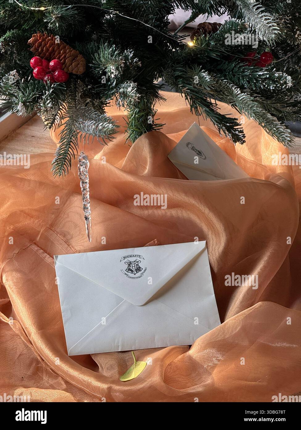 Weihnachtsbaum mit festlichen Briefumschlägen auf orangefarbenem Stoffhintergrund, perfekt für Weihnachtsthemen. Mobiles Foto Stockfoto