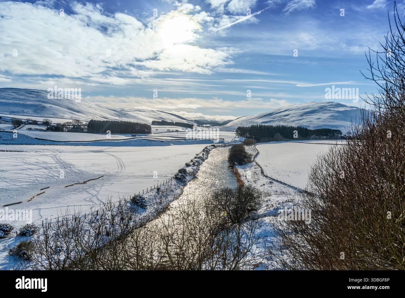 Schneebedeckte Felder und ein glitzernder Fluss in einem ruhigen Yarrow-Tal unter einem klaren blauen Himmel. Stockfoto
