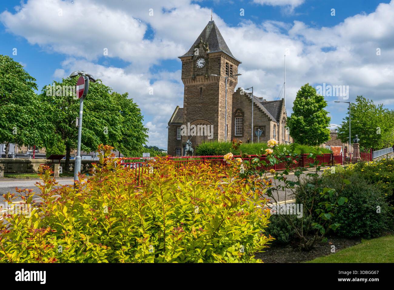Historische Kirche in Galashiels mit einem Steinturm, Garten im Vordergrund und hellem Himmel. Stockfoto