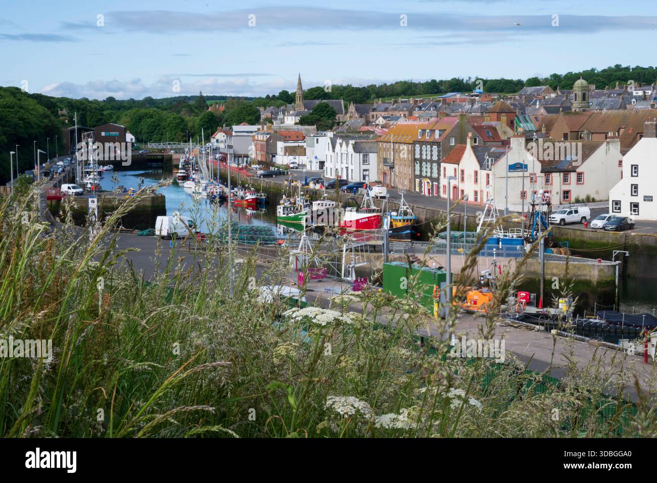 Hafenszene in Eyemouth mit Booten, Kai und farbenfrohen Häusern entlang der Uferpromenade. Stockfoto