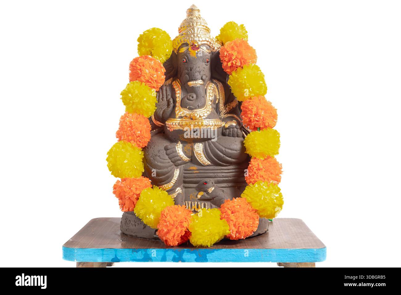 Ein Ganesha-Idol mit einer leuchtenden orange-gelben Blumengirlande auf einem Holzsockel. Geeignet für hinduistische Anbetung, festliche Dekoration, sp Stockfoto
