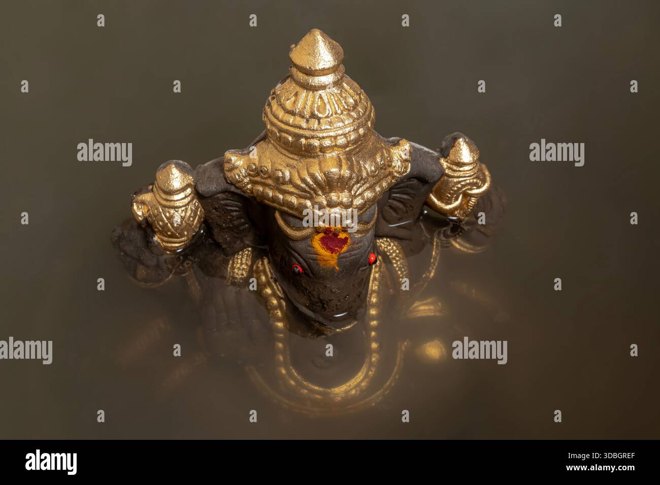 Ein wunderschön gefertigtes goldenes Ganesha-Idol, das teilweise in Wasser getaucht ist und das traditionelle Eintauchen während Ganesh Chaturthi repräsentiert. Stockfoto