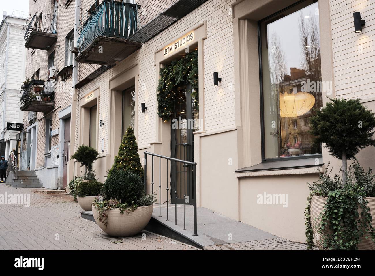 Feierlicher Eingang eines gemütlichen Studios in einer belebten Stadtstraße im Winter. Shevchenko Boulevard. Kiew, Ukraine. Dezember 2025. Stockfoto