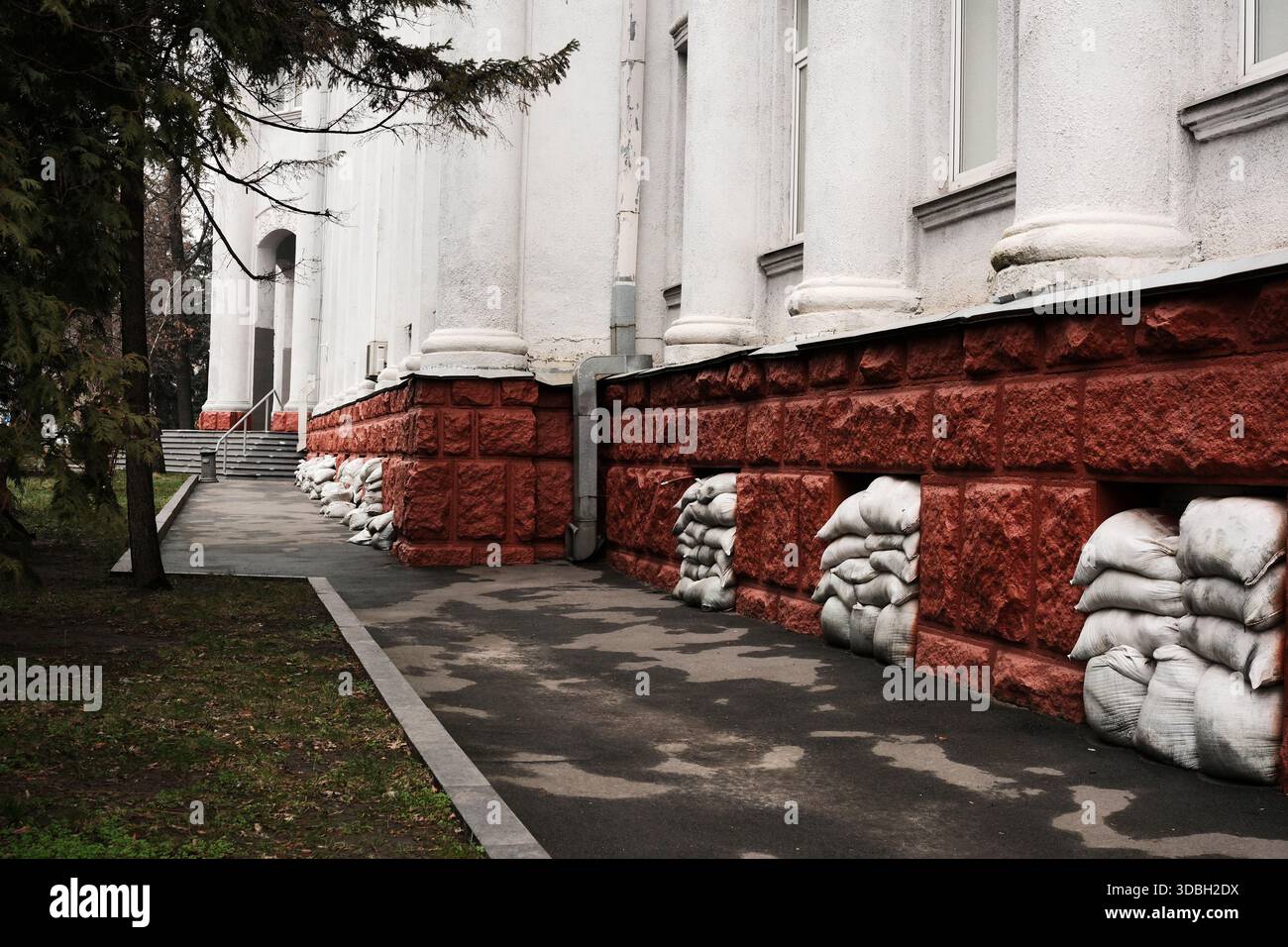 Farbenfrohe Taschen säumen die Basis eines Gebäudes und verleihen der Szene auf dem Bürgersteig künstlerisches Flair. Shevchenko Boulevard. Kiew, Ukraine. Dezember 2025. Stockfoto