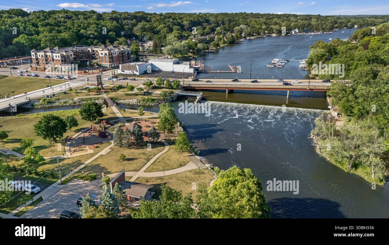 Blick aus der Vogelperspektive auf die Innenstadt von Algonquin Illinois entlang des Fox River mit Straßenlandschaften am Flussufer, Brückenüberquerung, Yachthafen und lokalen Unternehmen. Stockfoto