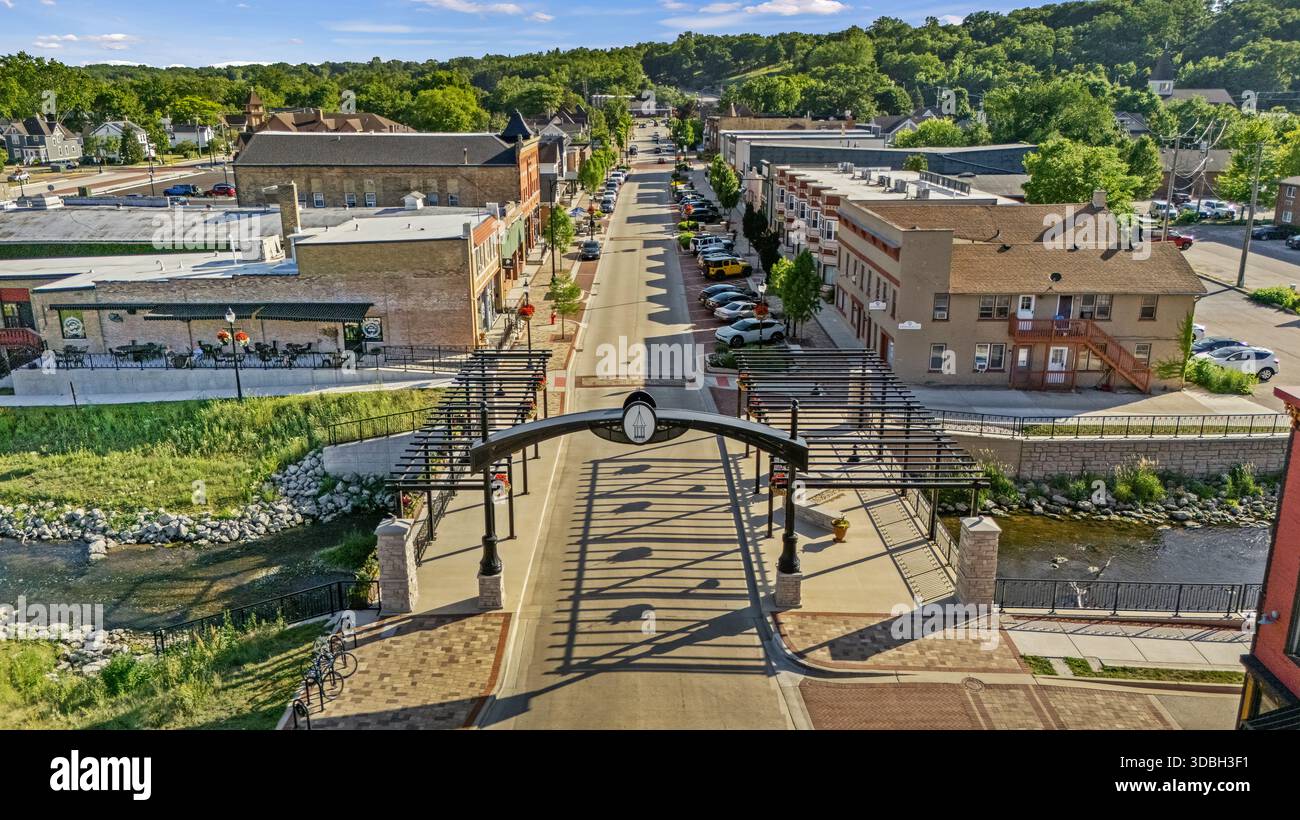Blick aus der Vogelperspektive auf die Innenstadt von Algonquin Illinois entlang des Fox River mit Straßenlandschaften am Flussufer, Brückenüberquerung, Yachthafen und lokalen Unternehmen. Stockfoto