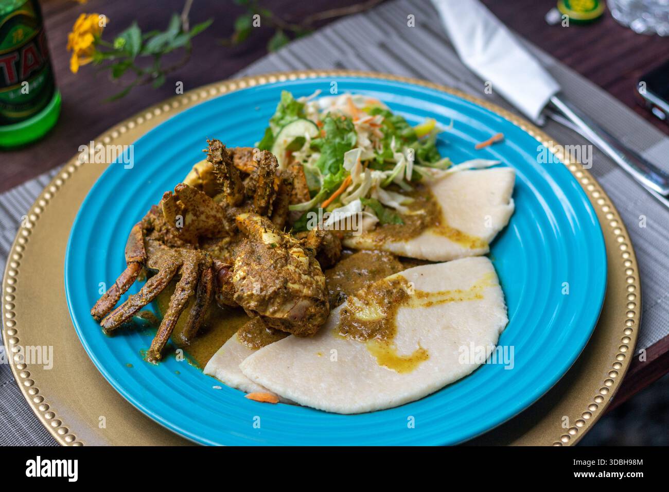 Currykrabben und Knödel serviert auf einem blauen Teller, ein traditionelles Tobago-Gericht mit karibischer Küche und Inselkultur. Stockfoto