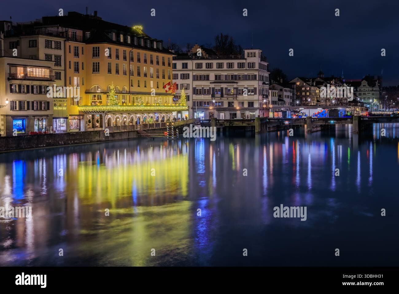 Stadtbild von Zürich, Schweiz, in der Abenddämmerung. Gebäude am Ufer der Limmat, die durch die Altstadt fließen, Boote entlang des Ufers Stockfoto