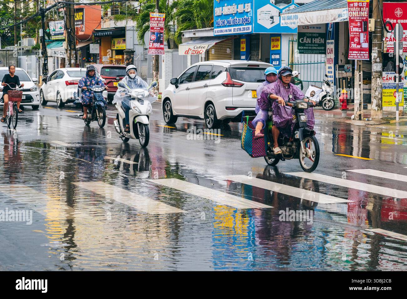 Vietnamesen Motorradfahrer auf Motorrädern und Autos fahren während der Regenzeit im Winter in Nha Trang in Asien bei starkem Regen die Straße entlang. Nha Trang, Vietnam - 13. Dezember 2024 Stockfoto
