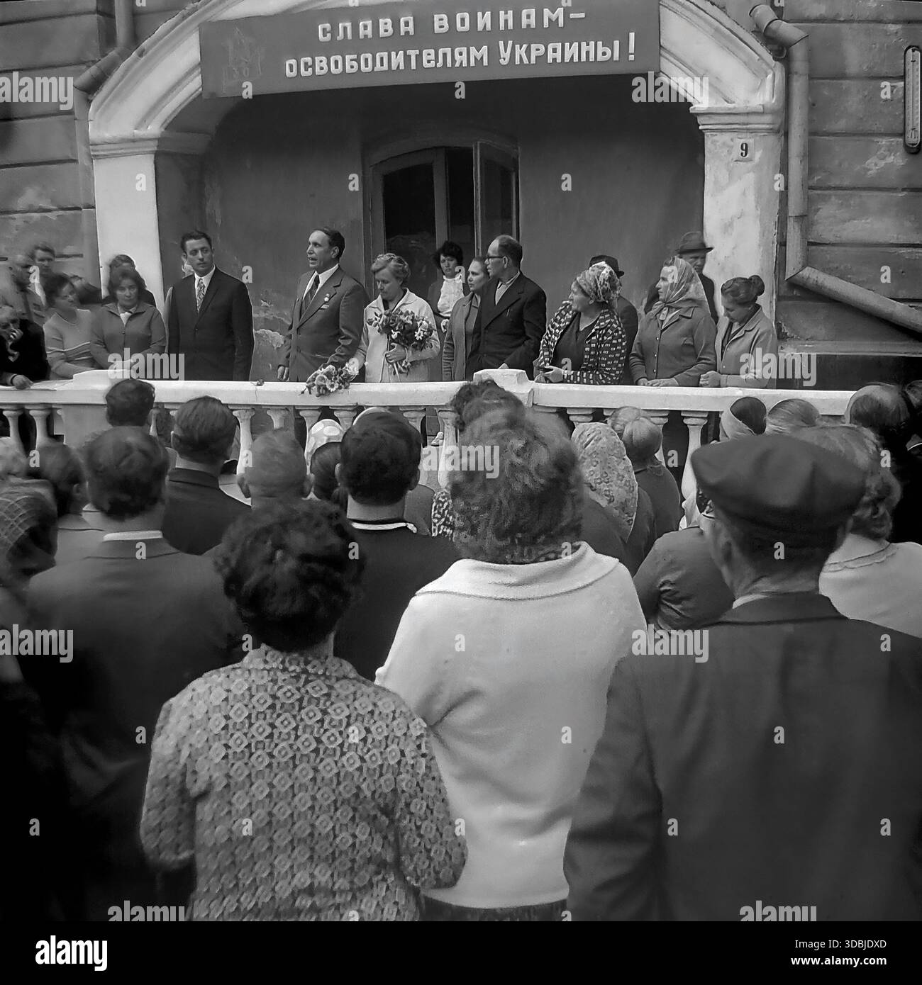September 1978. Slavyanogorsk (jetzt Sviatohirsk), Region Donezk, Ukrainische SSR, UdSSR. Der blinde Kriegsheld Shutenko steht auf der Tribüne während einer Massendemonstration, die dem 35. Jahrestag der Befreiung der Ukraine von der Nazi-Besatzung gewidmet ist. Auf einem Banner über dem Eingang steht: „Ruhm an die Krieger-Befreier der Ukraine!“. Eine Menschenmenge von Bewohnern hört den Lautsprechern zu. Authentisches Archivbild, das die Atmosphäre des Patriotismus und des friedlichen Lebens im sowjetischen Donbass erfasst. Stockfoto