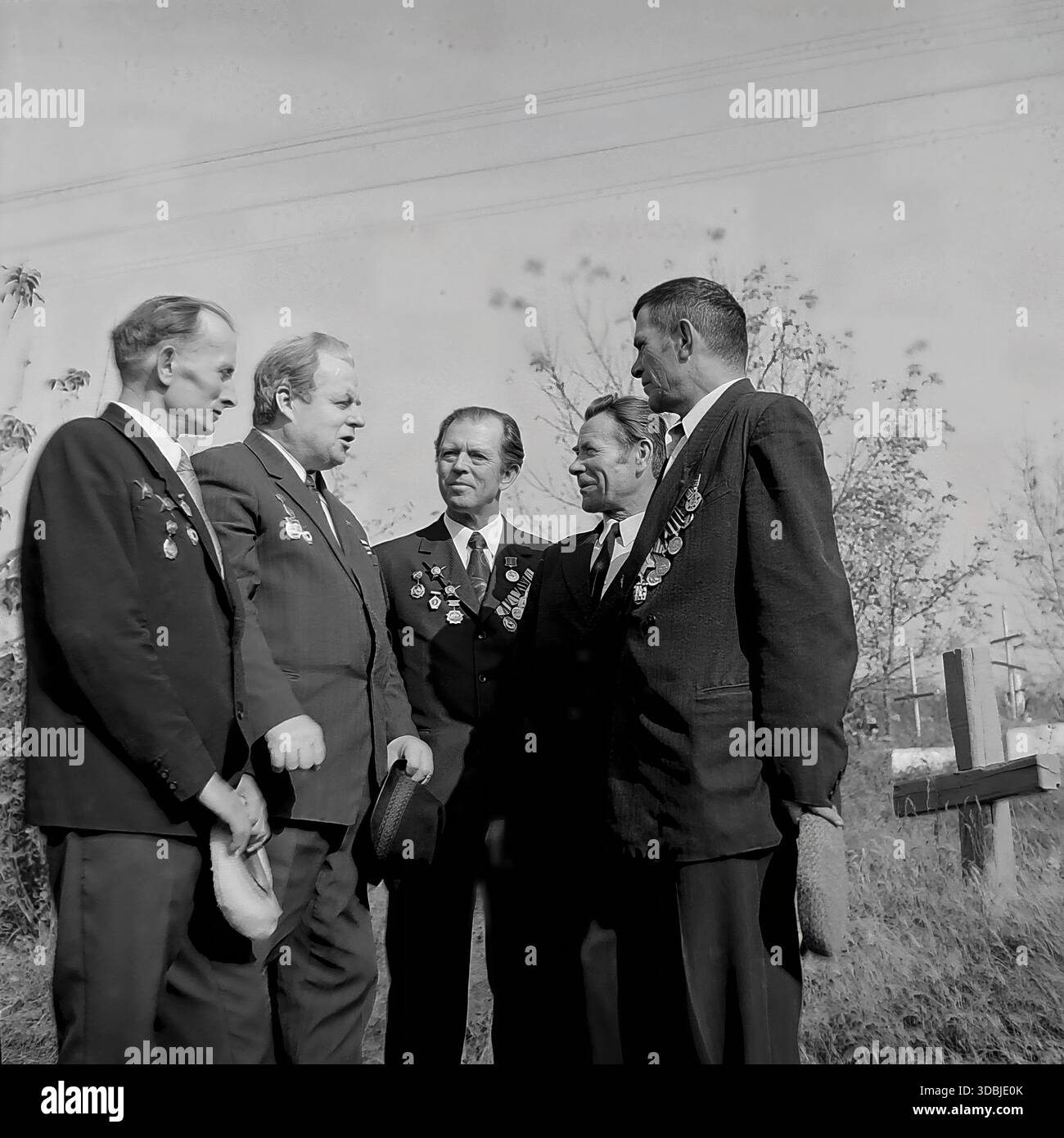 September 1978. Dorf Dolina, Bezirk Sloviansk, Region Donezk, ukrainische SSR, UdSSR. Eine Gruppe von fünf Veteranen des Zweiten Weltkriegs in Zivilanzügen mit Medaillen und Orden auf der Brust versammelt sich in der Nähe eines hölzernen Kreuzes. Die Männer halten Hüte in den Händen während eines freundlichen Treffens zum 35. Jahrestag der Befreiung des Dorfes von der Nazi-Besatzung. Authentisches Archivbild, das die Atmosphäre der Brüderlichkeit, des Gedächtnisses und des friedlichen Lebens im sowjetischen Donbass während der Breschnew-Ära erfasst. Stockfoto
