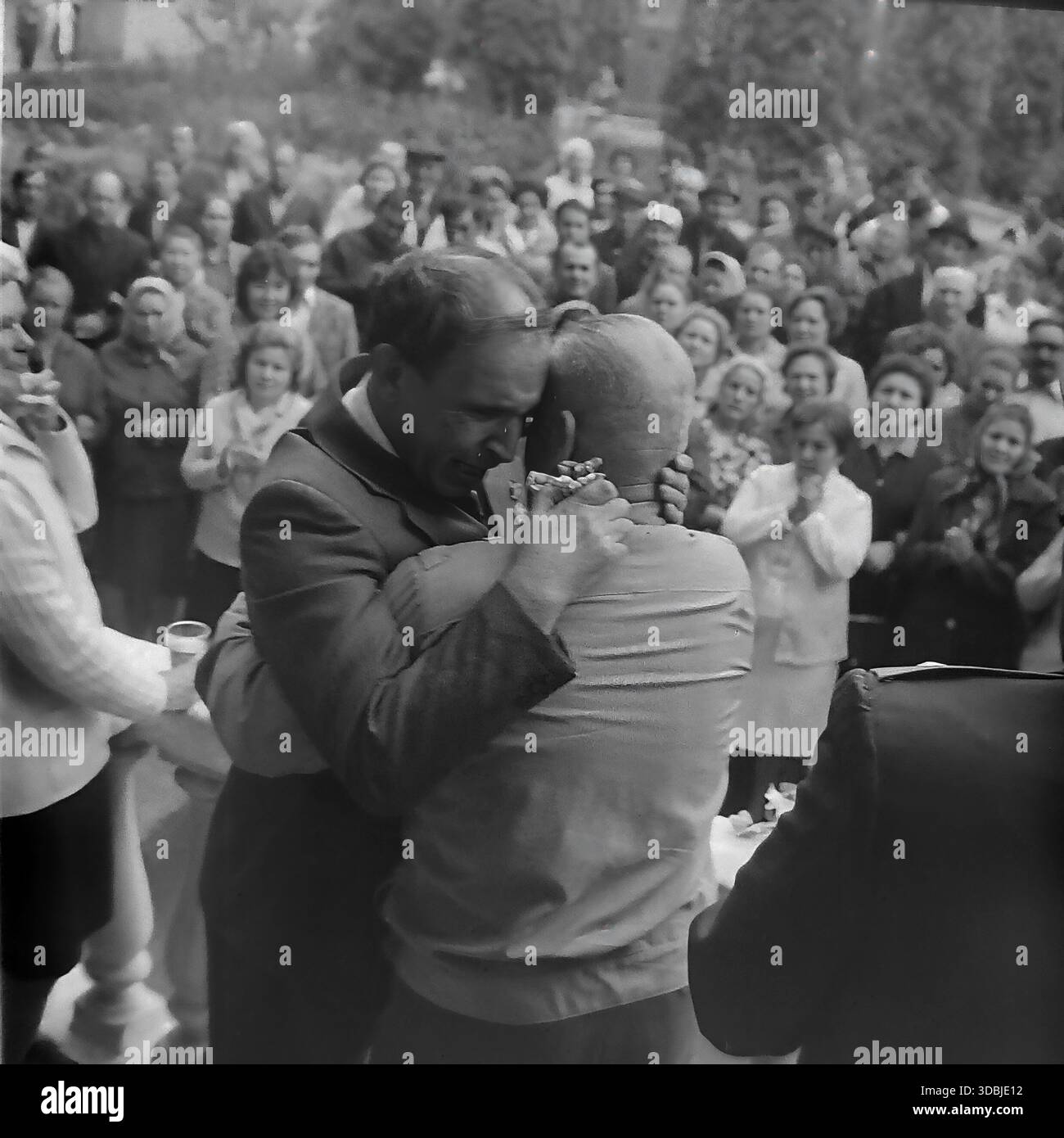 September 1978. Slavyanogorsk (jetzt Sviatohirsk), Region Donezk, Ukrainische SSR, UdSSR. Der blinde Kriegsheld Shutenko umarmt einen Kameraden in einer SoldatenTunika auf einem Balkon während einer Kundgebung zum 35. Jahrestag der Befreiung der Ukraine. Eine Menschenmenge von Einwohnern beobachtet das emotionale Wiedersehen der Veteranen von unten. Authentisches Archivbild, das die Atmosphäre der Bruderschaft und des friedlichen Lebens im sowjetischen Donbass feststellt. Stockfoto