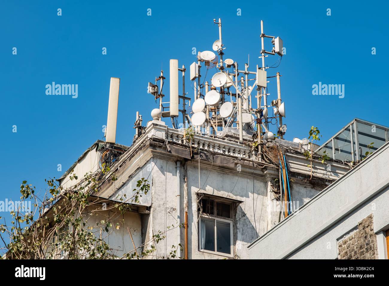 Handymasten auf einem Hausdach. Viele Richtantennen des 5G-Mobilfunknetzes auf dem Dach eines Wohngebäudes. 5G- und 4G-Mobilfunkmasten Stockfoto