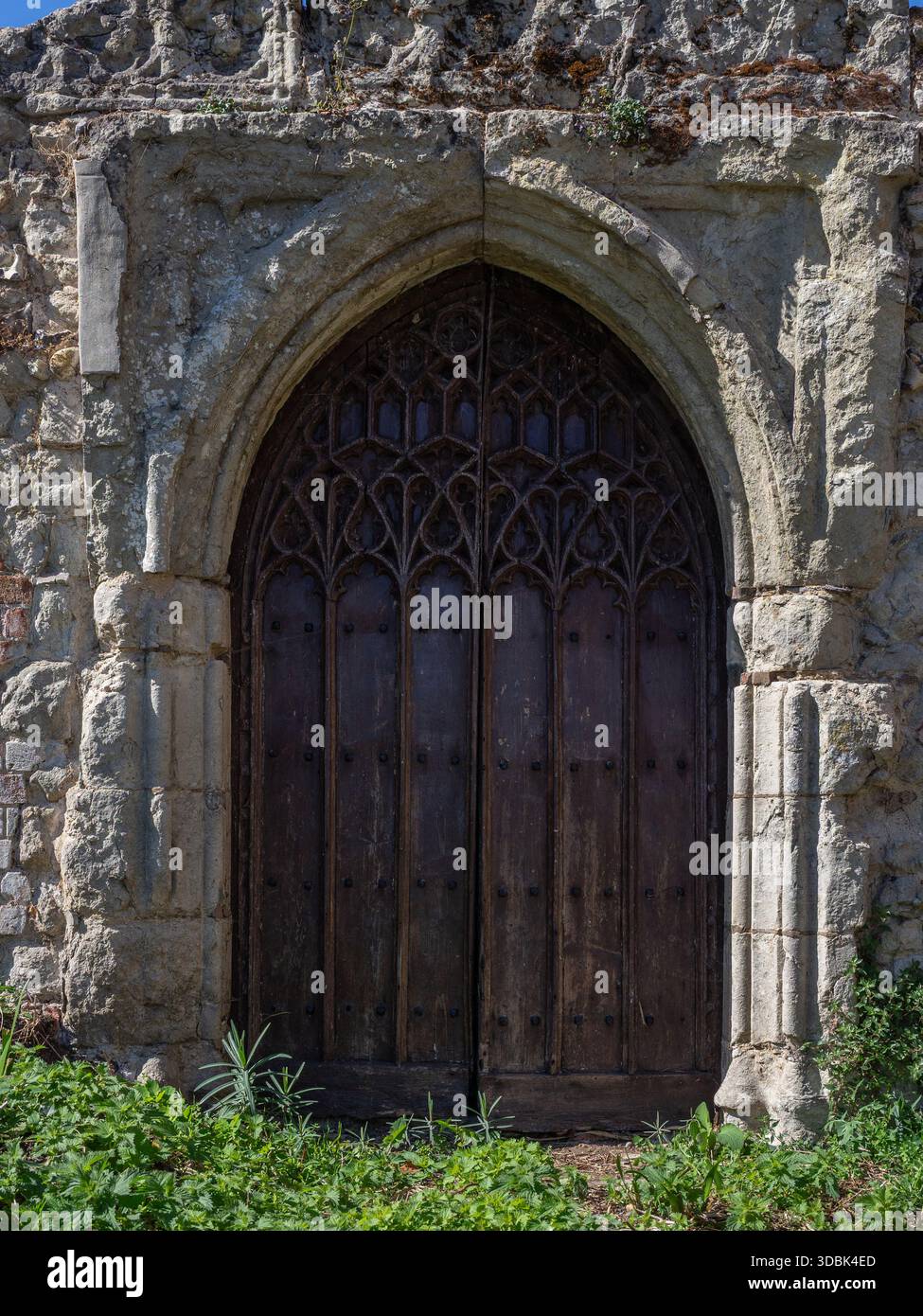Alte Holztür in einer kunstvoll geschnitzten Steinumrandung, möglicherweise der Überrest eines früheren Gebäudes aus dem 15. Jahrhundert, Kirchhof, Hadleigh, Suffolk, Großbritannien Stockfoto