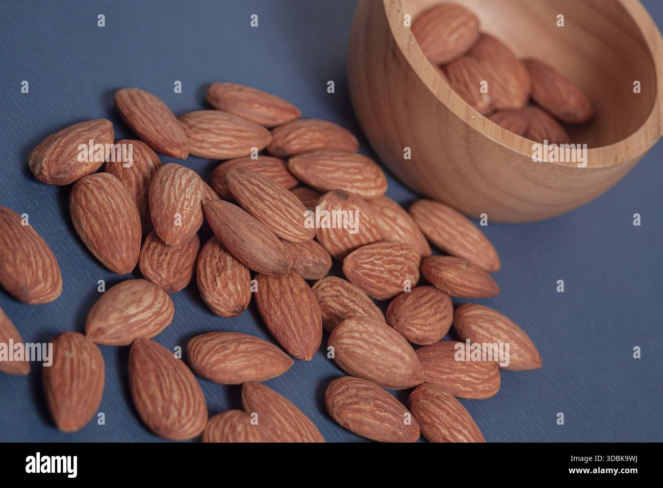 Mandeln liegen auf einem einfachen Blatt Papier auf und betonen ihre natürliche Textur in einer sauberen minimalen Szene. Stockfoto