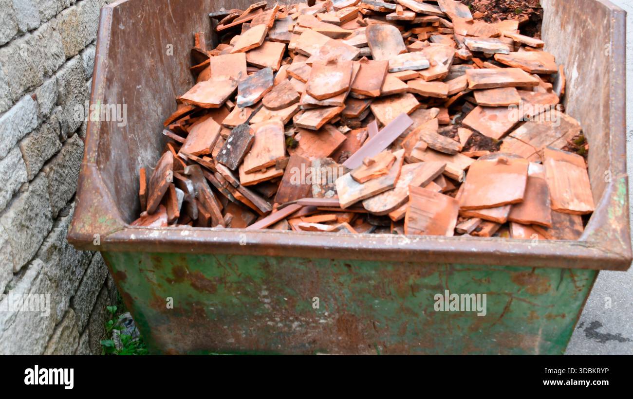 Zertrümmerte Dachziegel im Bauschutt-Container Stockfoto